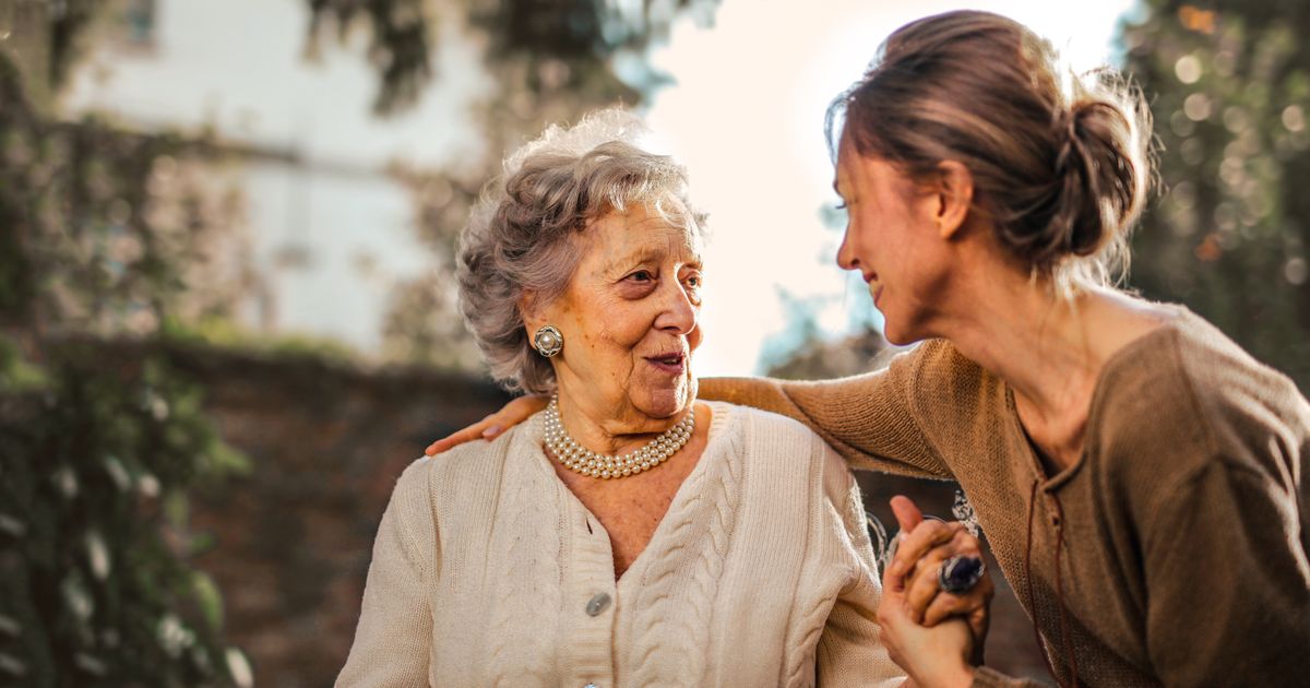 Adult daughter and senior mother sharing a warm moment together in a sunlit garden