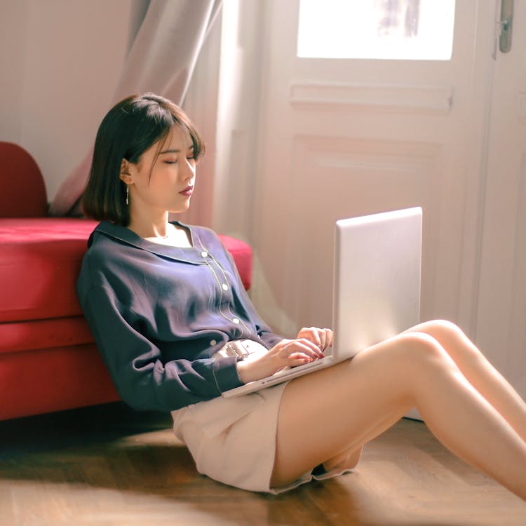 Woman Sitting on Floor While Using Laptop
