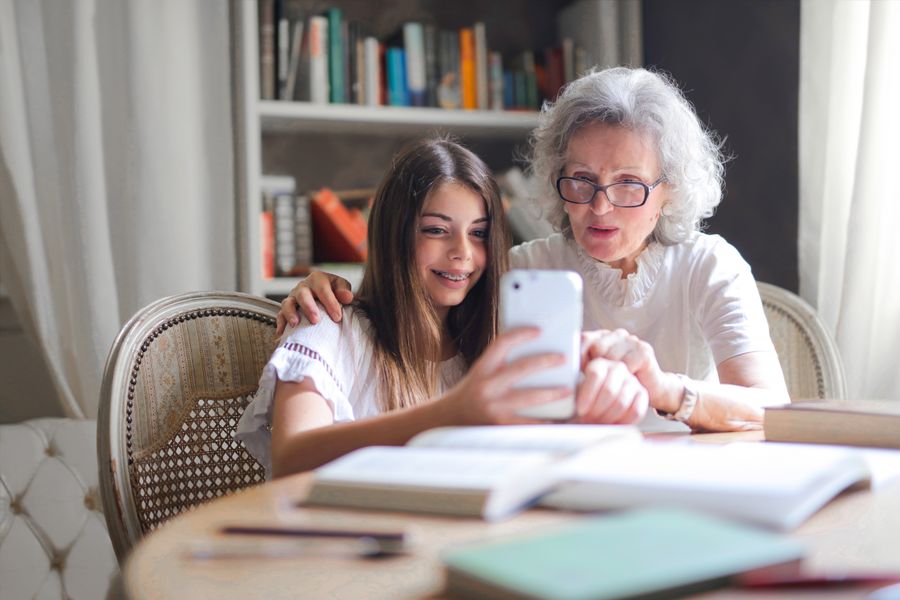 Una nieta le muestra algo en el celular a su abuela, ambas sonriendo