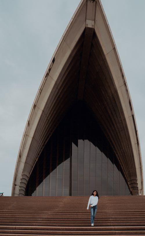 Free A person walking on the steps of Sydney Opera House, showcasing its unique architecture. Stock Photo