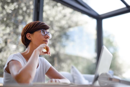 一位戴着眼镜、留着短发的体贴女人，在现代风格的房间里望着窗外