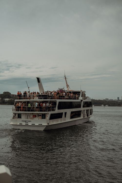 Free A cruise ship filled with people enjoying a day on Sydney Harbor under a cloudy sky. Stock Photo