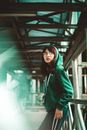 一位戴眼镜的年轻女子倚靠在城市环境中的金属栏杆上