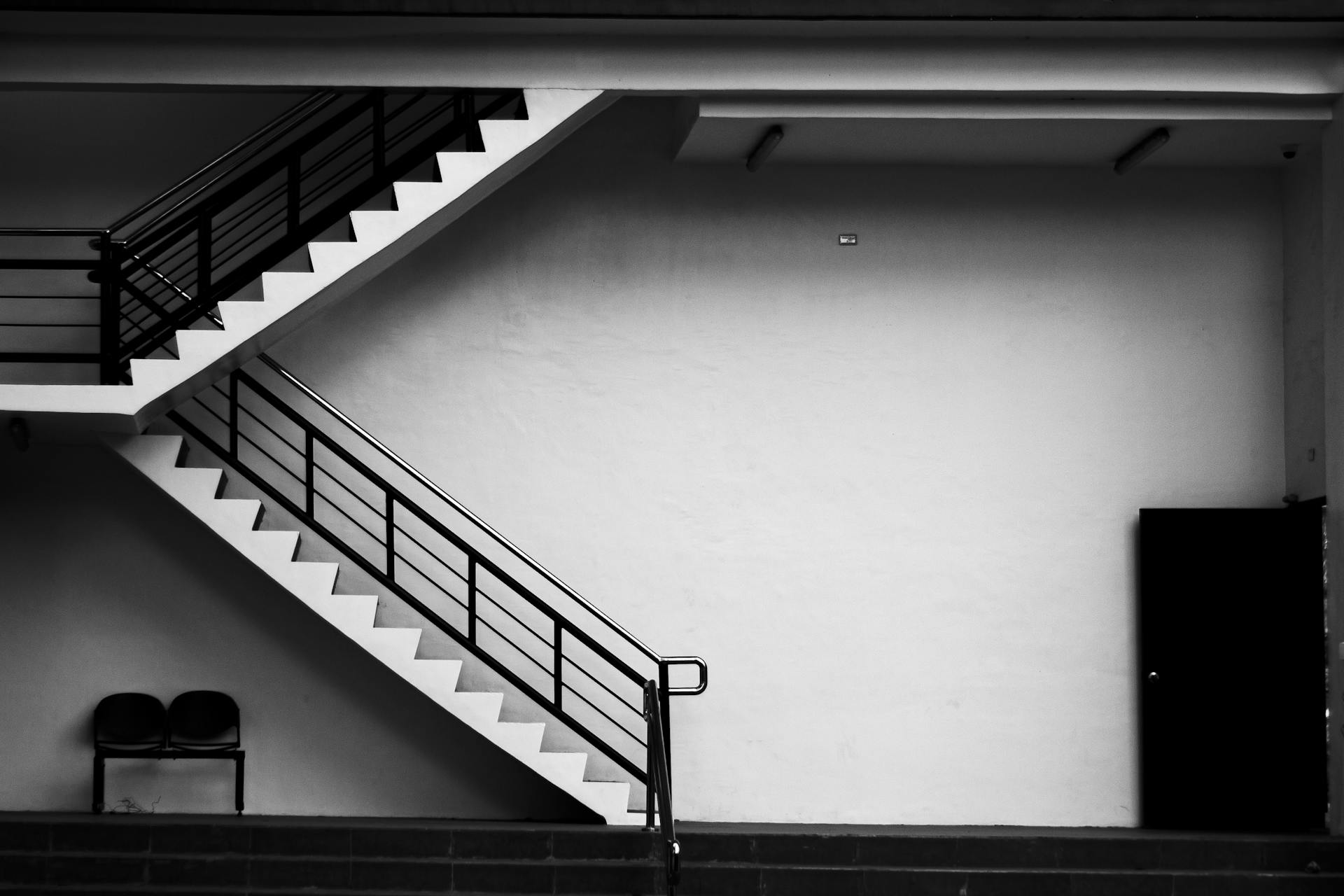 Black and white photo of a modern staircase featuring sharp lines and minimalist design.