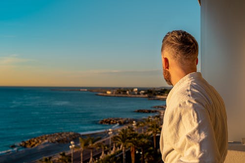 Man Wearing Bathrobe While Looking Out in the Scenery