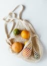 Assorted citrus fruits in cotton sack on white surface