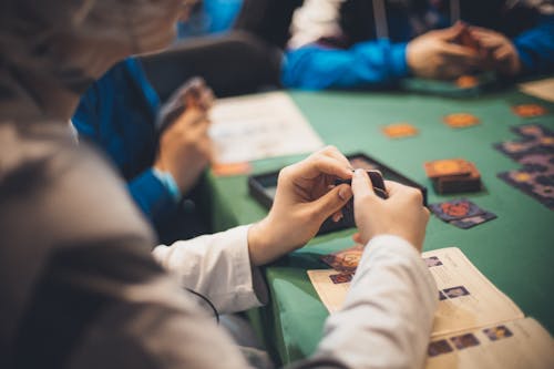 Crop people playing cards at table