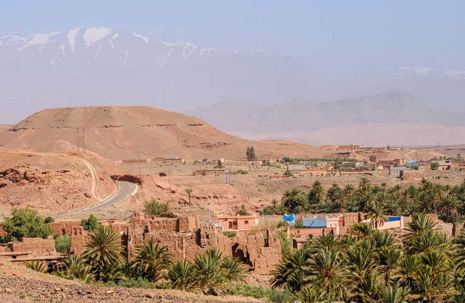 Picturesque view of Moroccan landscape with Atlas Mountains and palm trees.
