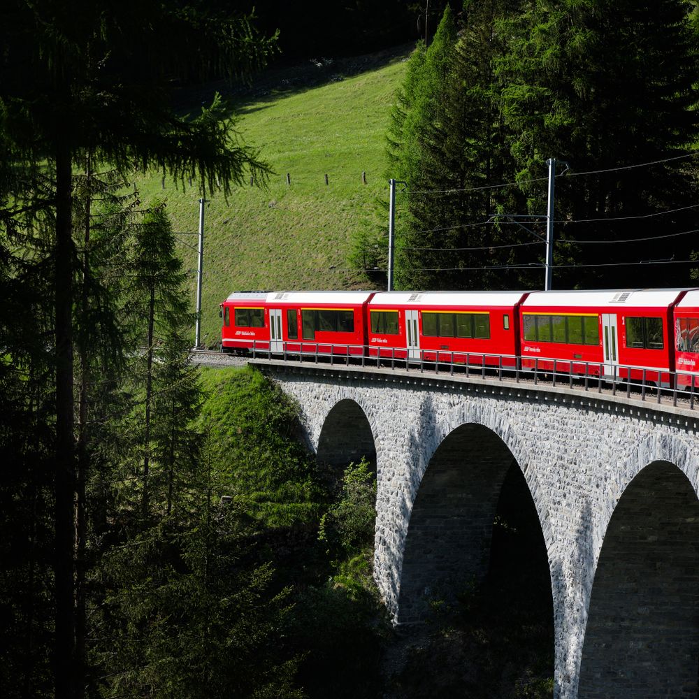 Tren roșu pe un viaduct de piatră în Alpii Elvețieni