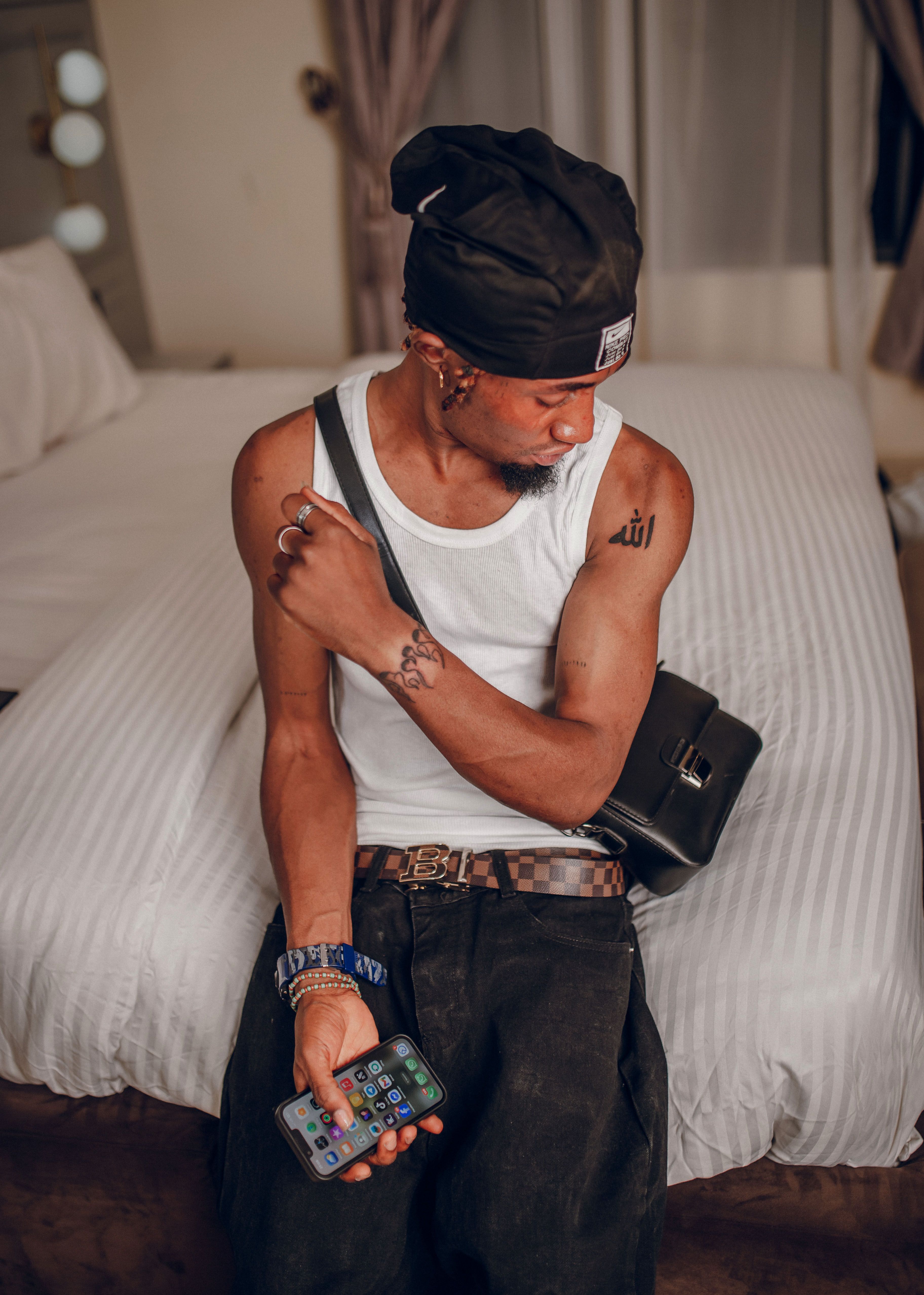 Fashionable young man looking at his tattoo in urban setting, showcasing style and personality.