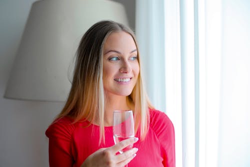 Free Женщина в розовой рубашке с длинным рукавом с прозрачным стаканом Stock Photo
