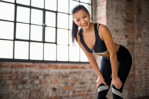 Fit woman in sportswear smiling after a workout in an industrial-style gym.