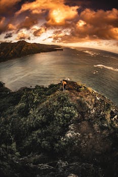 Stunning aerial view of a coastal cliff at sunset with dramatic skies and ocean vista.