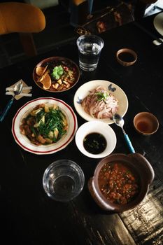 A beautifully arranged Asian food spread featuring various traditional dishes and drinks on a dark wooden table.