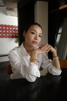 Elegant woman in a white shirt posing indoors with a confident gaze.