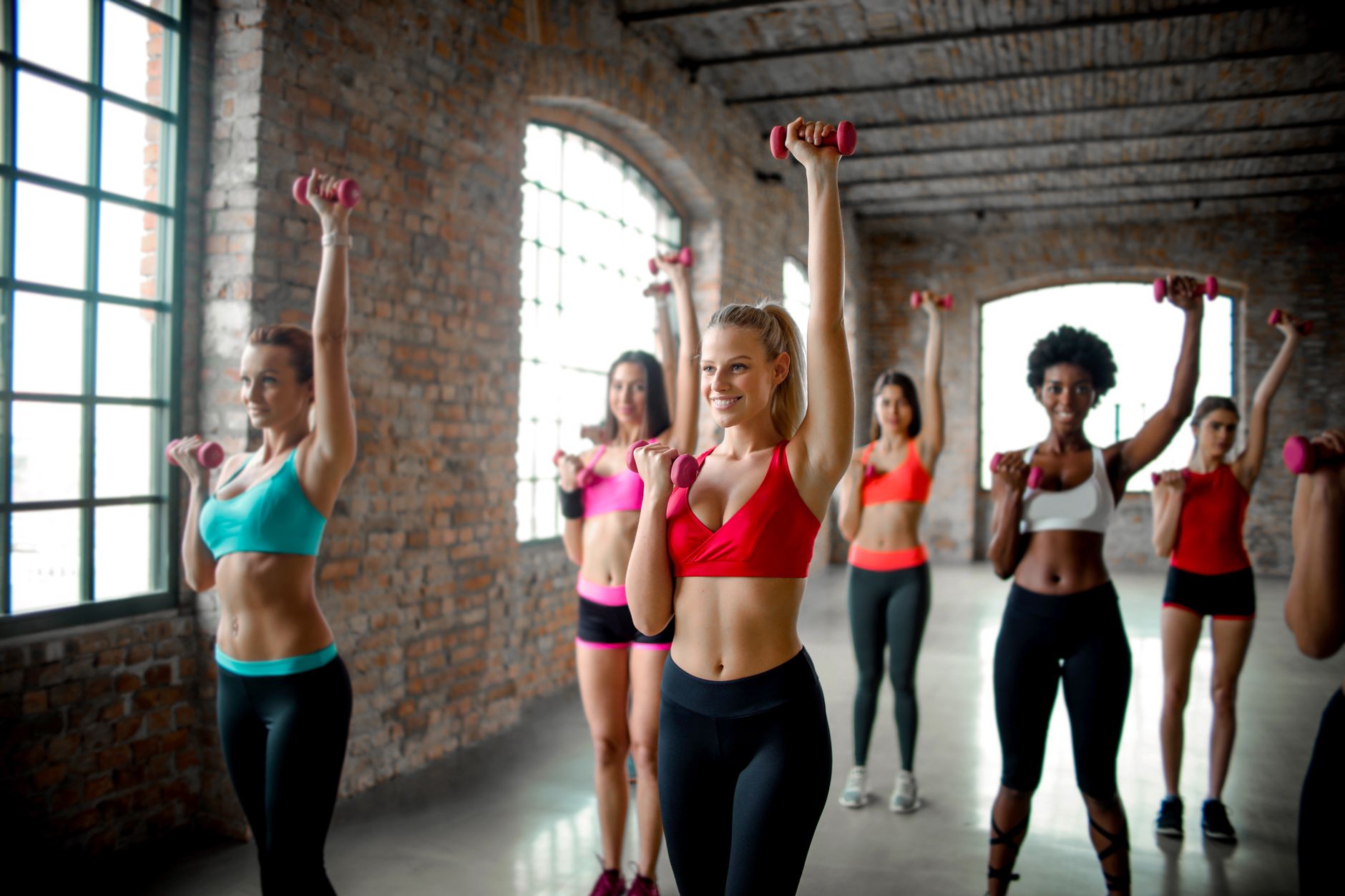 Energetic women working out with dumbbells in a bright indoor gym setting, embracing fitness and health.