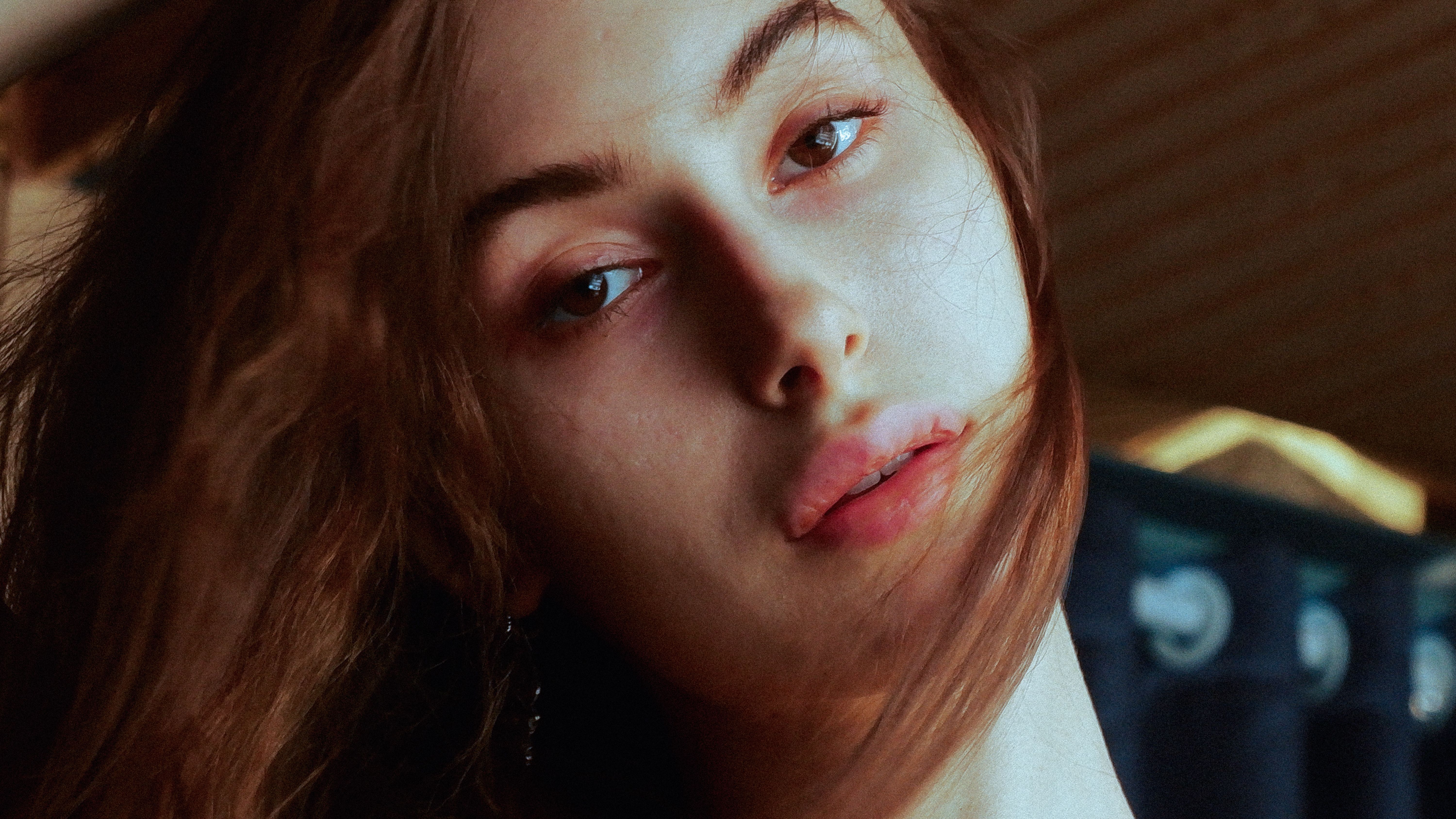 Artistic and moody close-up portrait of a young woman with flowing hair and intense gaze.