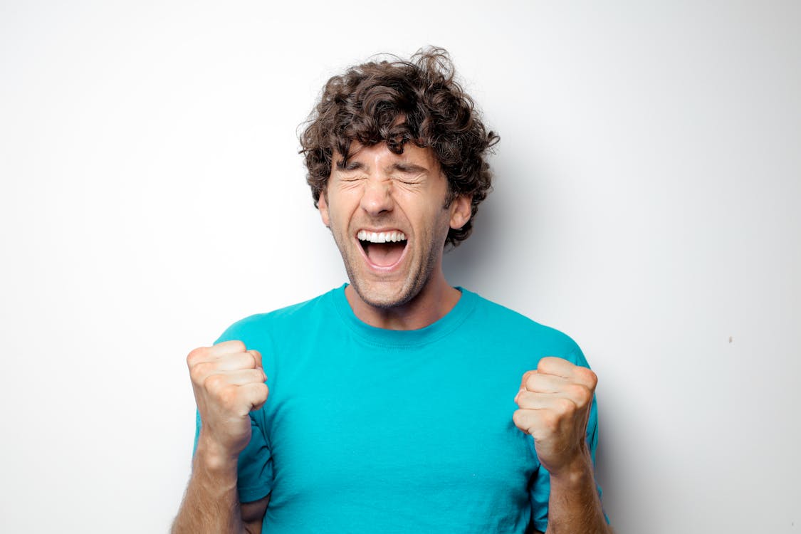 Portrait Photo of Excited Man in Blue T-shirt Standing In Front of White Background