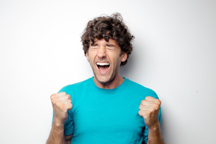 Portrait Photo Of Excited Man In Blue T-shirt Standing In Front Of White Background