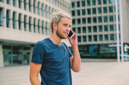 Free Man in Blue Crew Neck T-shirt Holding Smartphone Stock Photo