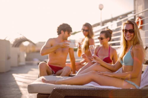 Glückliche Freunde, Die Leckeres Getränk Beim Gemeinsamen Sonnenbaden Am Strand An Sonnigem Sommertag Trinken