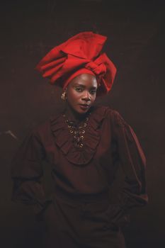 Portrait of a woman in traditional Nigerian attire, wearing a vibrant red headwrap.