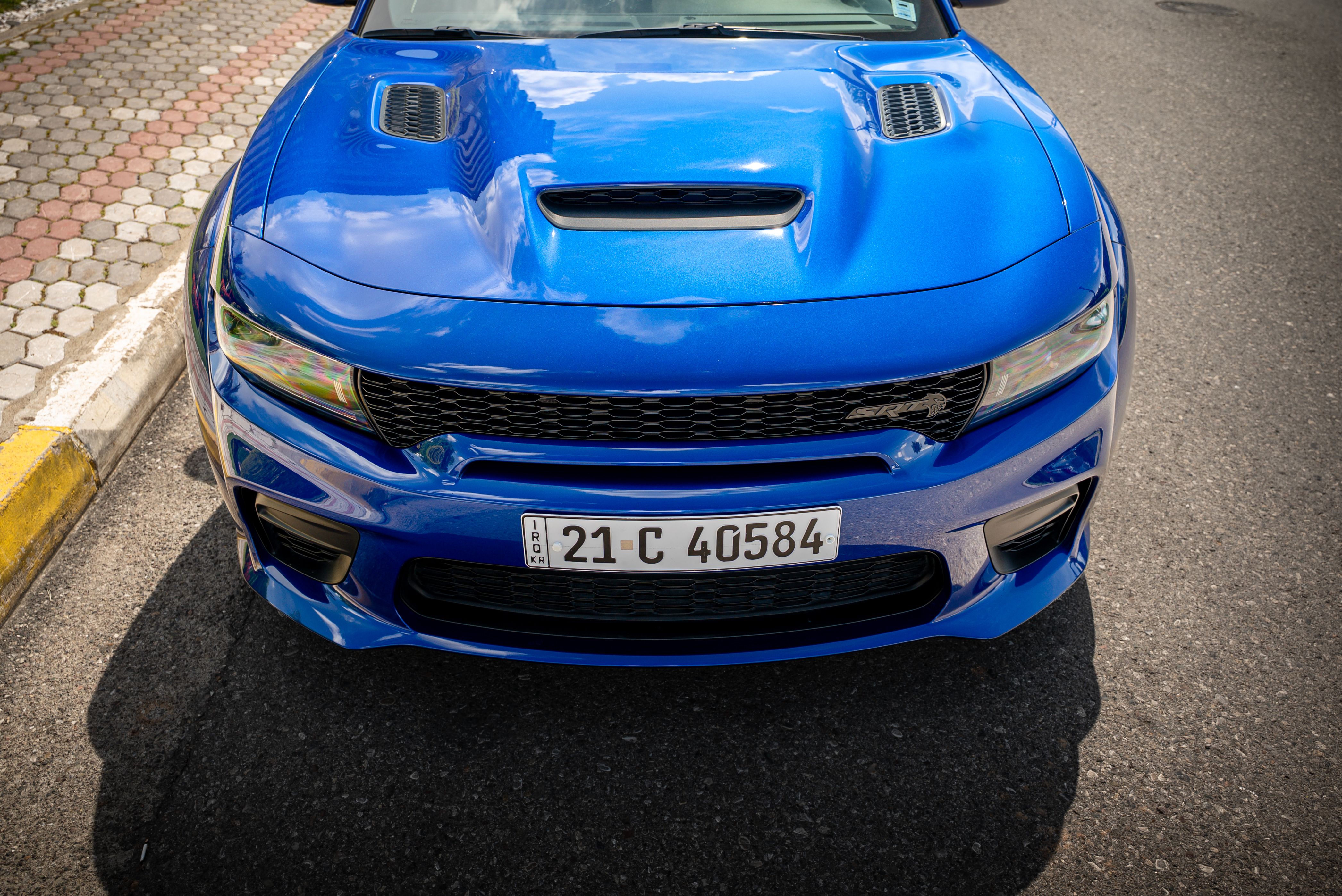 Vibrant blue sports car front view on city street, showcasing sleek design and dynamic color.
