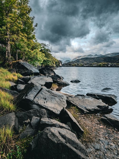 Free Scenic view of rugged rocks and lush greenery by a serene lake in Killarney, Ireland. Stock Photo