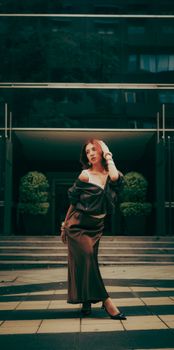 Stylish woman posing in a luxurious, modern urban environment during dusk.