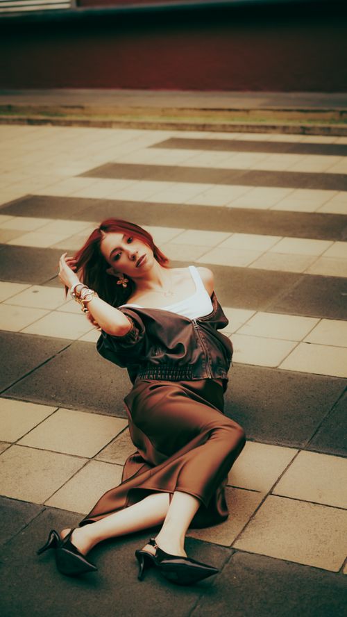 Free Fashionable woman in a brown outfit poses on a tiled urban walkway, exuding modern elegance. Stock Photo