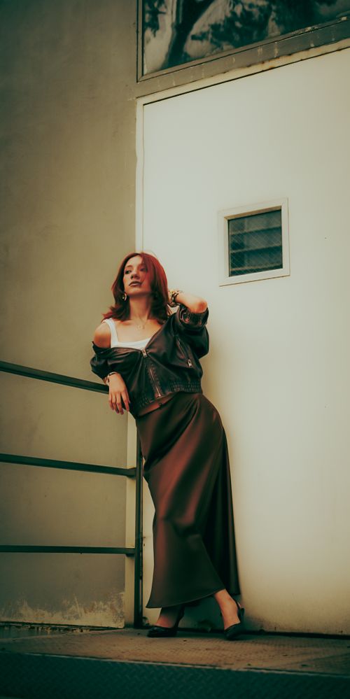 Free Stylish woman in autumn outfit posing against modern architecture with dramatic lighting. Stock Photo