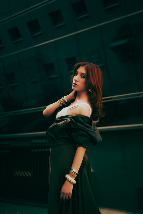 Free Stylish woman posing in a city backdrop with dramatic lighting. Stock Photo