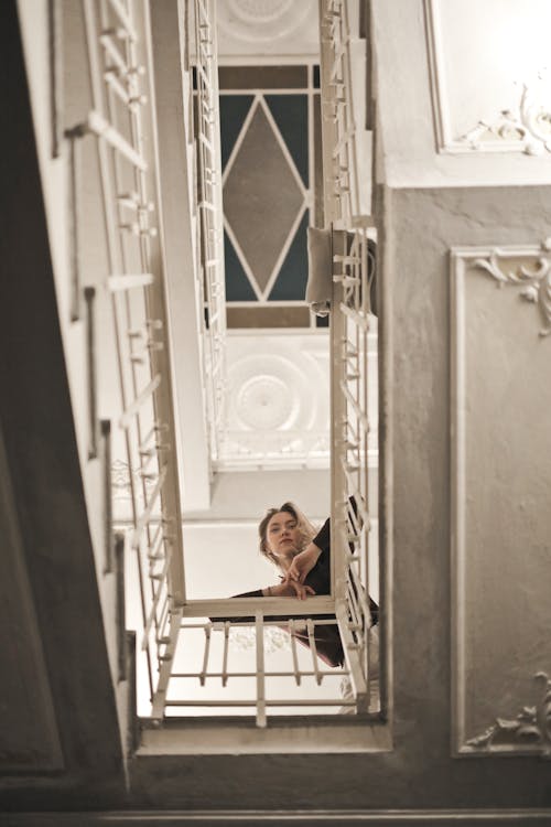 Low Angle Photo of Woman Leaning on Metal Railings