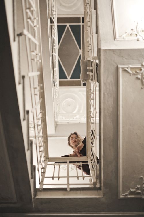 Free Low angle shot of a woman looking up from a vintage stairway with ornate details, enhancing elegance. Stock Photo