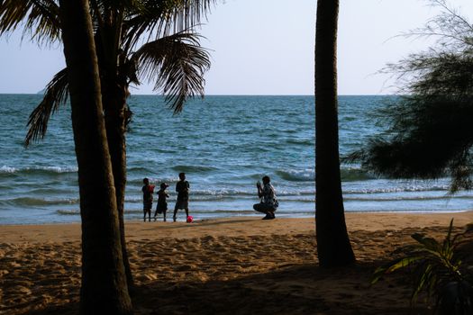 A family having fun on a sunny beach in Chanthaburi, Thailand, with children playing by the sea.