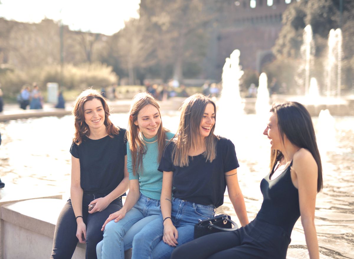Four friends laughing together outdoors beside a fountain. Photo by Andrea Piacquadio on Pexels