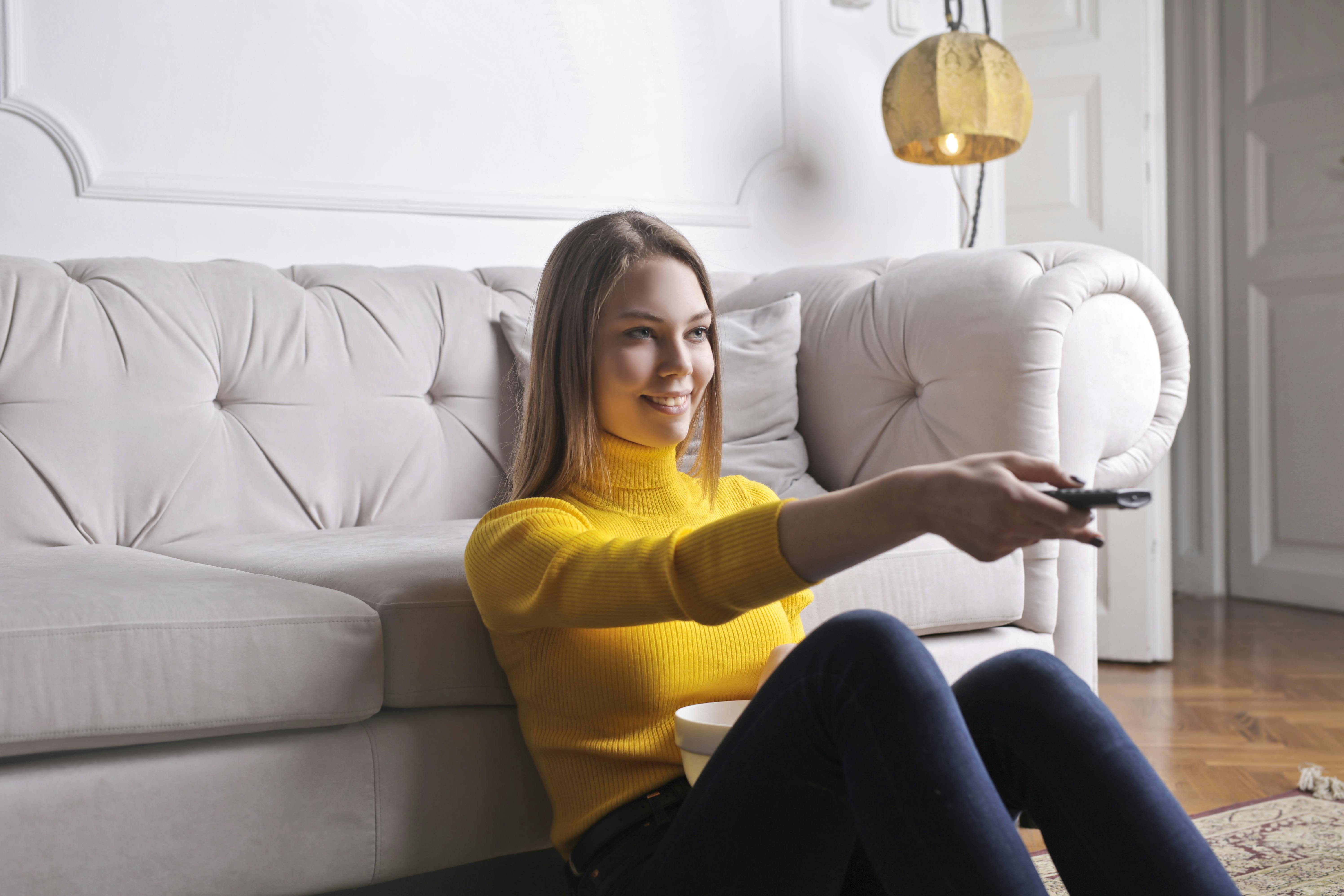 happy young relaxed woman watching tv at home