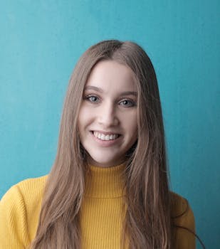 一位开朗的年轻女子穿着黄色毛衣，在蓝色背景下微笑