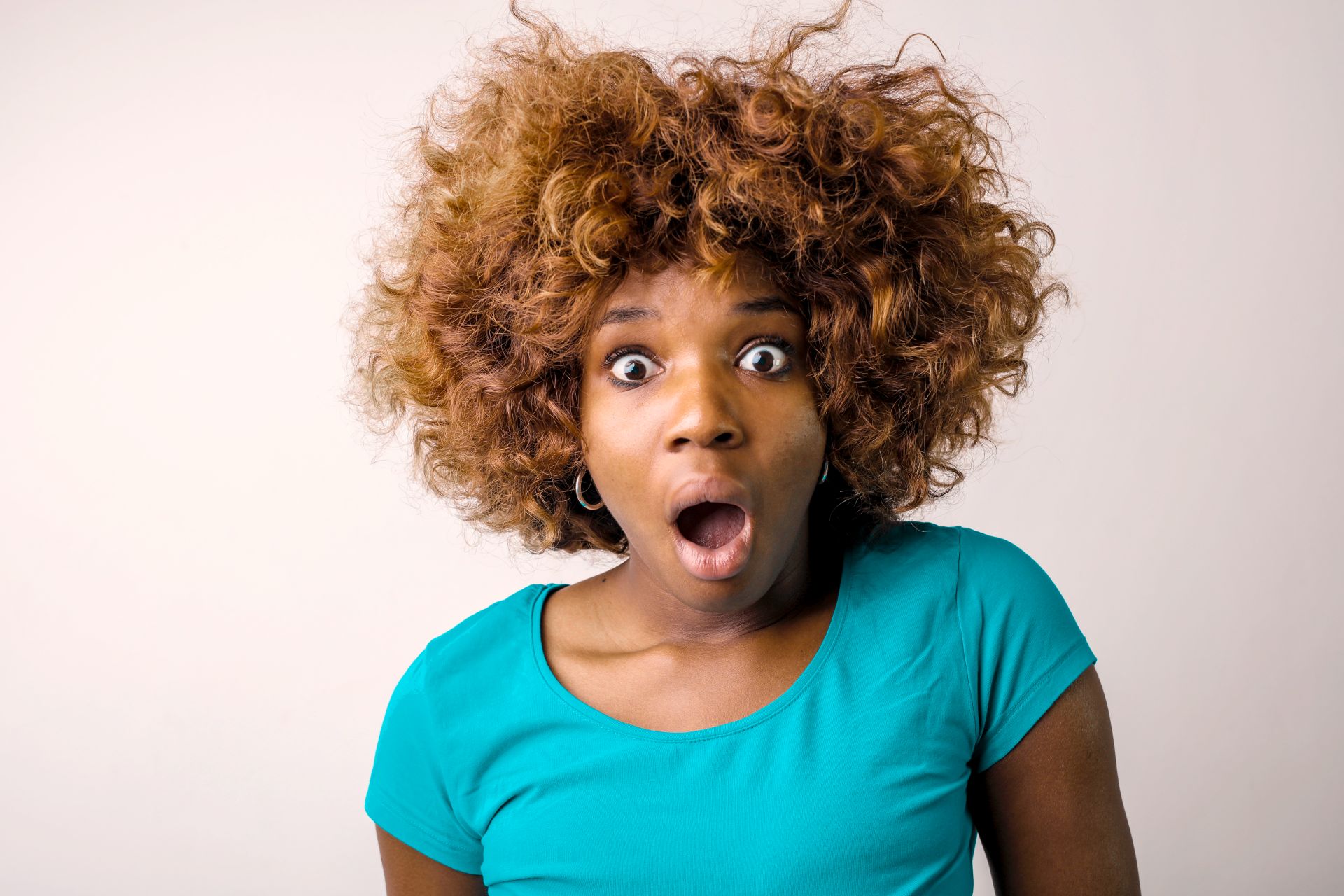 Portrait Photo of Shocked Woman in Blue T-shirt Standing In front of White Background