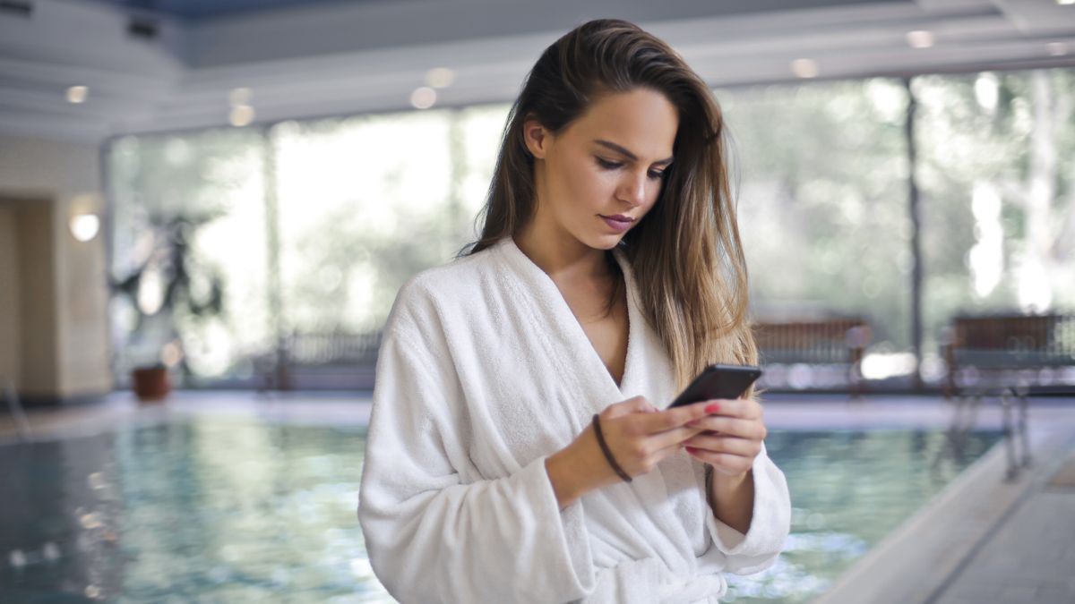 A traveler by a hotel pool checking prices on a smartphone