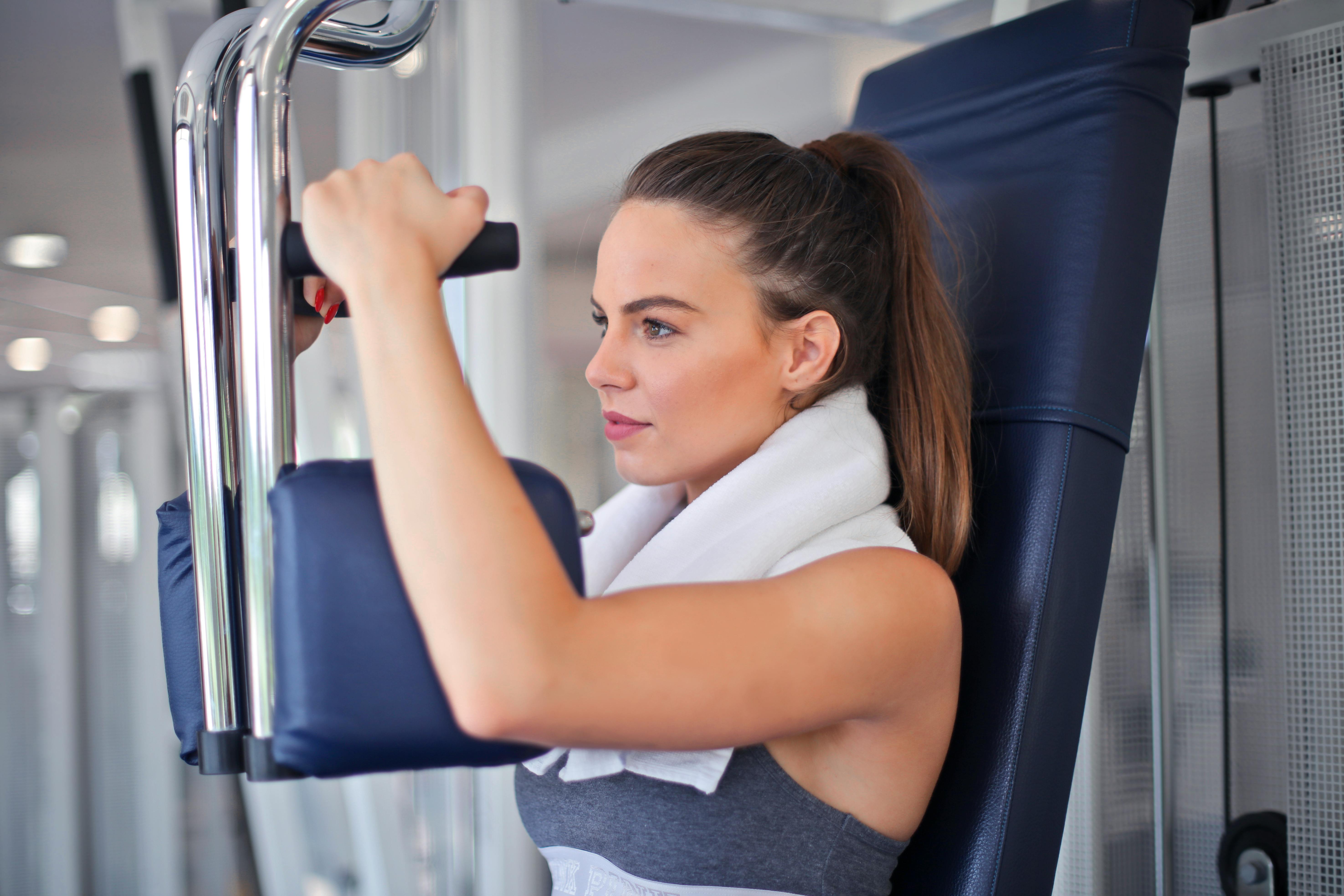 young determined sportswoman doing exercise on weight machine in modern sports club