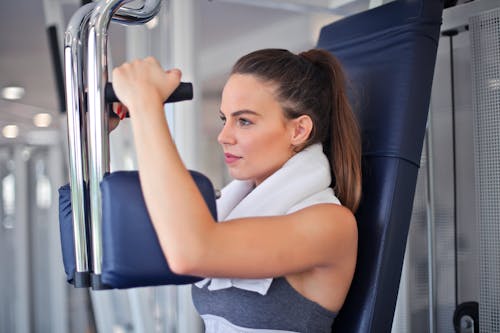 Free Young determined sportswoman doing exercise on weight machine in modern sports club Stock Photo
