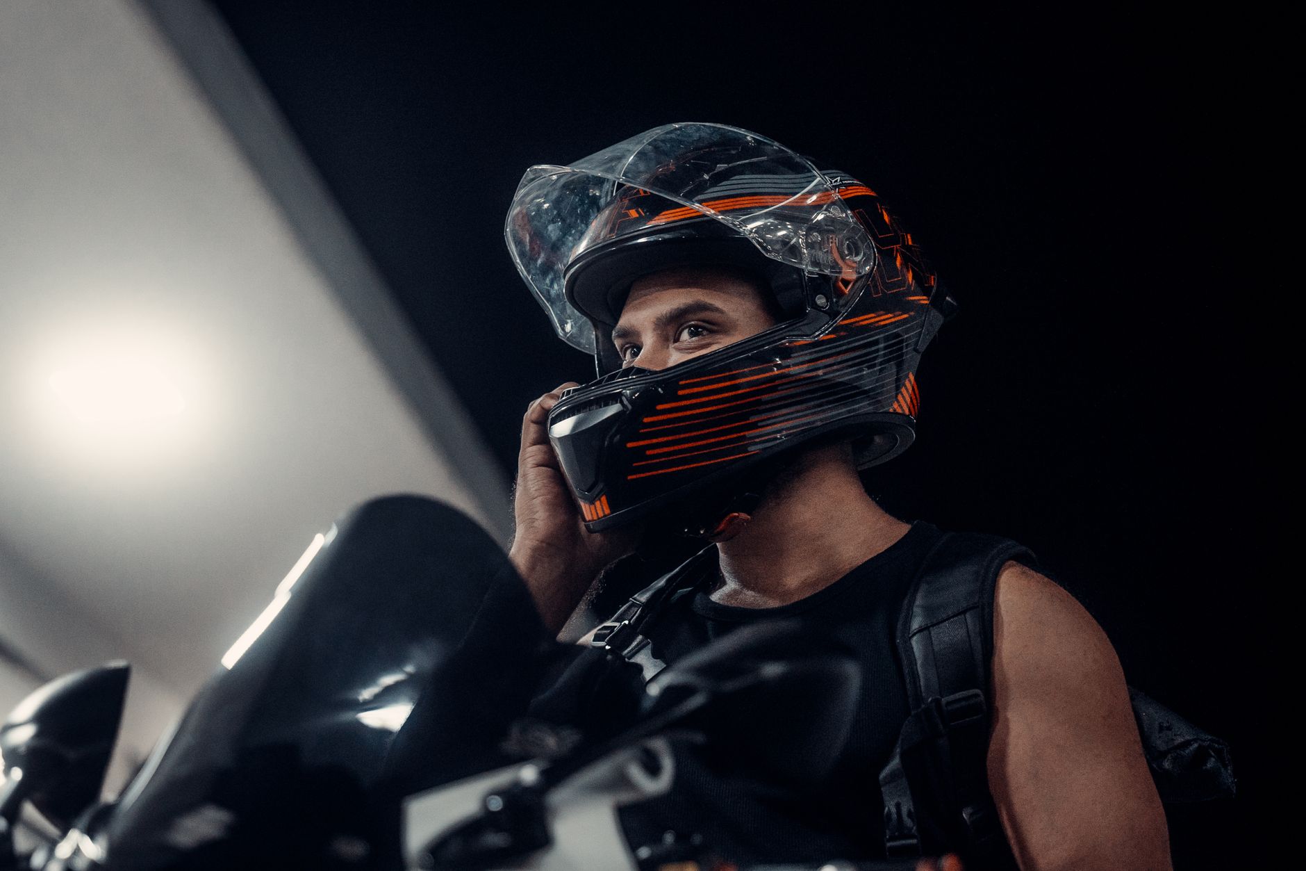 A motorcyclist with a helmet talks on the phone at night in the streets of Dhaka, Bangladesh.