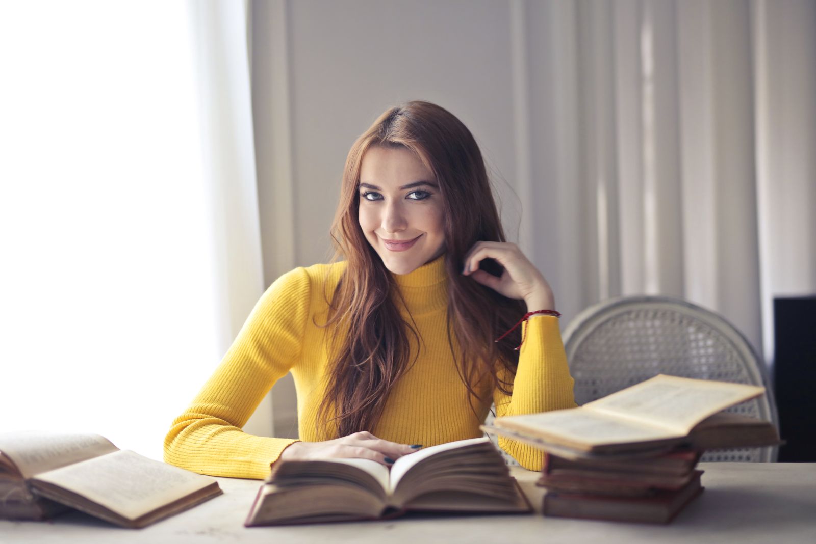 Person holding shoulder and neck area while sitting in bright natural light