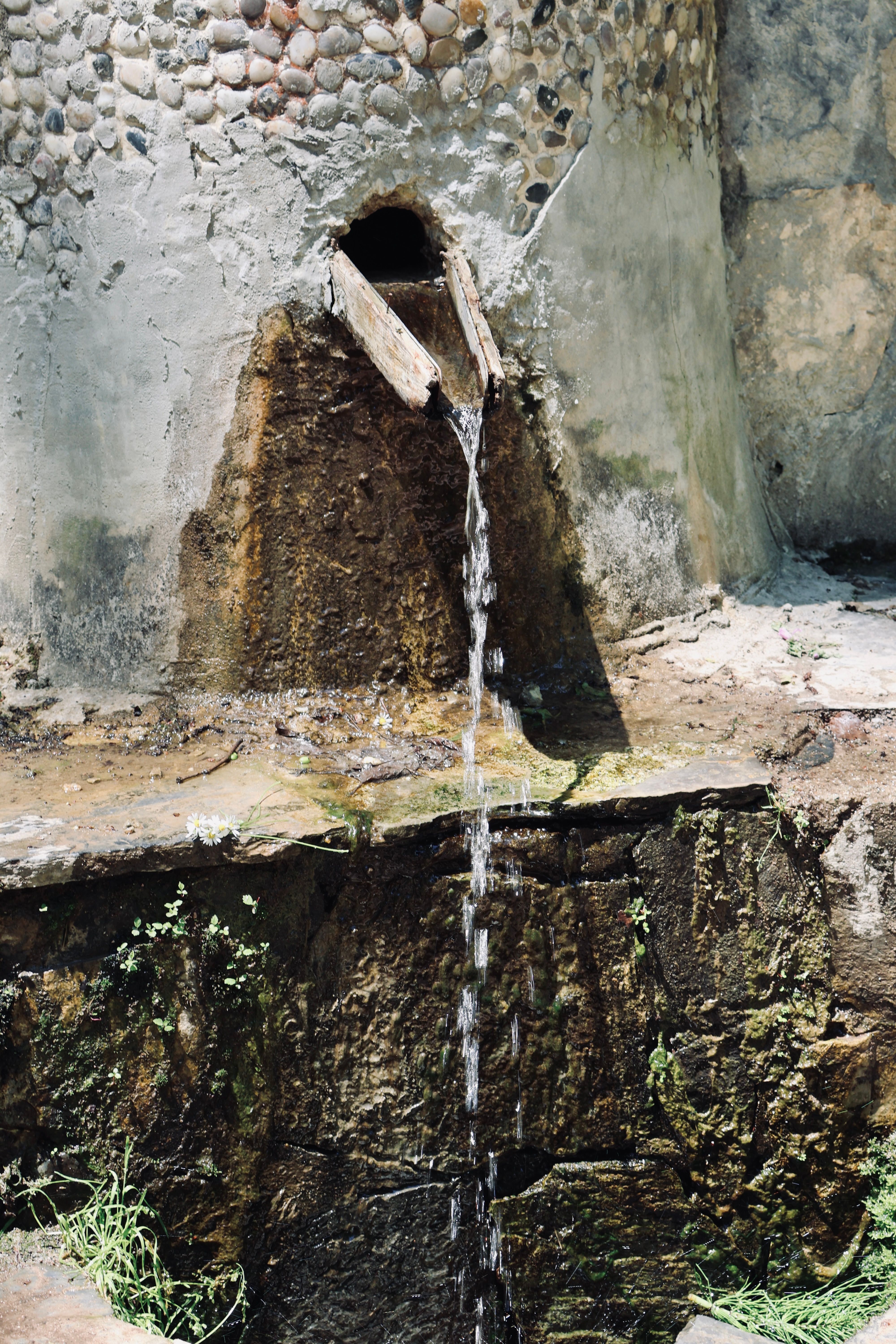 Rustic Water Feature in Sunlit Stone Wall · Free Stock Photo