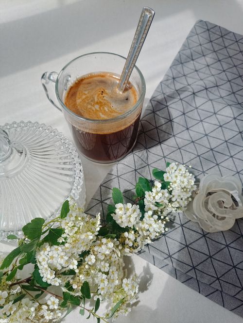 Free A cup of espresso with a spring floral arrangement on a modern table setting. Stock Photo