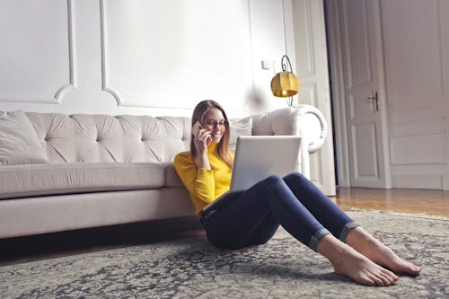 Glückliche Erwachsene Frau, Die Am Telefon Spricht Und Laptop Beim Kühlen Zu Hause Verwendet