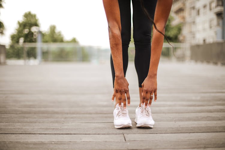 Slim Woman Warming Up While Training Alone On Street Sports Ground