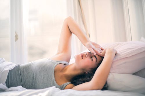 Free Woman in Gray Tank Top Sleeping On White Bed Stock Photo