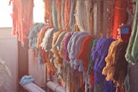 Skeins of multicolored threads for needlework hanging on wooden rack in light workroom